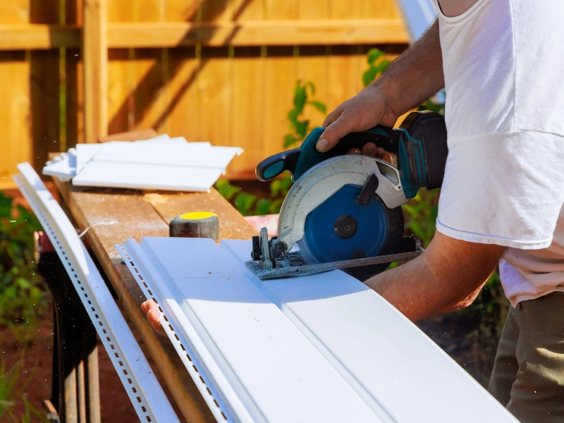 Image of a contractor prepping the siding of the home before painting vinyl siding.